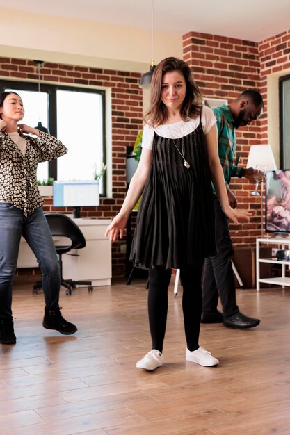 Diverse groep jonge mensen dansen in de woonkamer op een wijnfeestje terwijl ze hun verjaardag vieren. Vrolijke vrienden die een feest hebben voor een vriendschapsjubileum terwijl ze alcoholische dranken drinken.