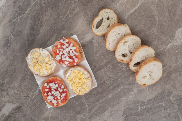 Gratis foto diverse heerlijke bruschetta op witte plaat met sneetjes brood. hoge kwaliteit foto