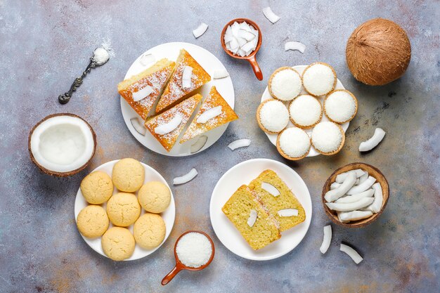 Diverse heerlijke kokos snoepjes, koekjes, cake, marshmallow, kokosvlokken en halve kokosnoot, bovenaanzicht