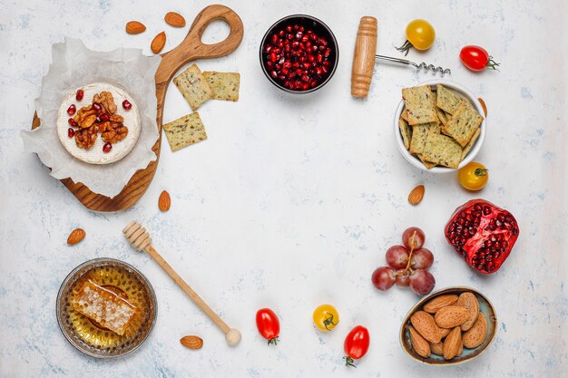 Diverse kaas en kaasplaat op lichte tafel met verschillende noten en fruit