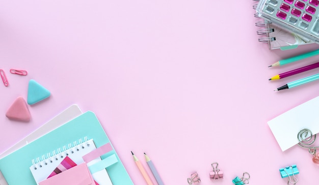 Diverse kleurrijke kantoorbehoeften voor school en kantoor op roze achtergrond met copyspace.