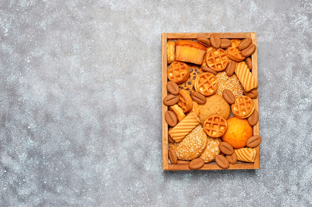 Diverse koekjes in een houten dienblad op grijze oppervlakte