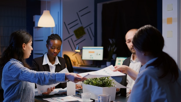 Gratis foto diverse multi-etnische zakenmensen delen management grafieken papierwerk overwerk in kantoorvergadering...