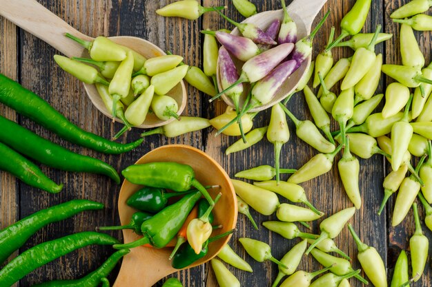 Diverse paprika's in houten lepels op houten, plat lag.