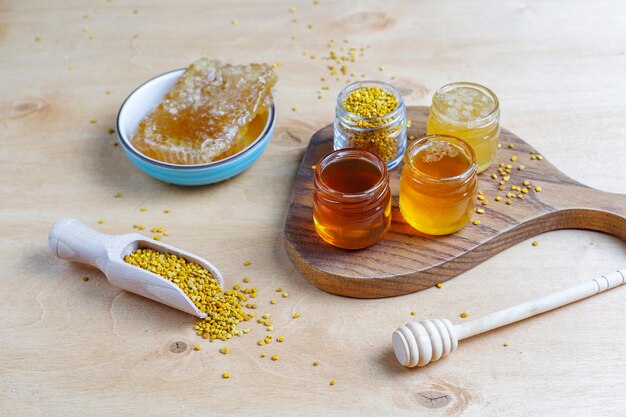 Diverse soorten honing in glazen potten, honingraat en pollen