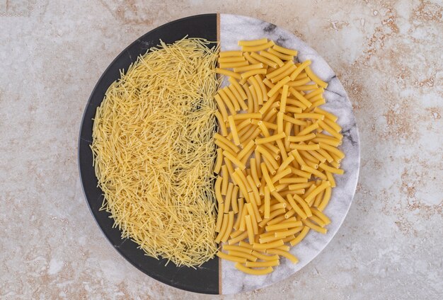 Diverse soorten ongekookte macaroni op een mooi bord