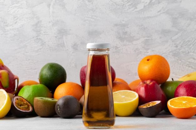 Diverse vruchten en vers geperst vruchtensap in fles op grijze achtergrond Premium Foto