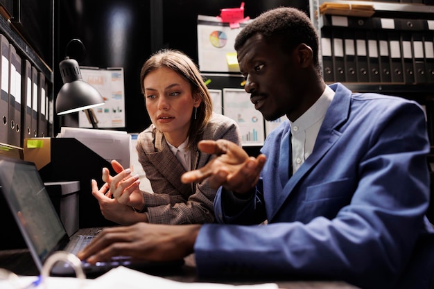 Diverse zakenmensen werken overuren aan boekhoudrapport, analyseren administratieve documenten in opslagruimte. Depository-medewerkers lezen bureaucratierecords, organiseren bedrijfsbestanden