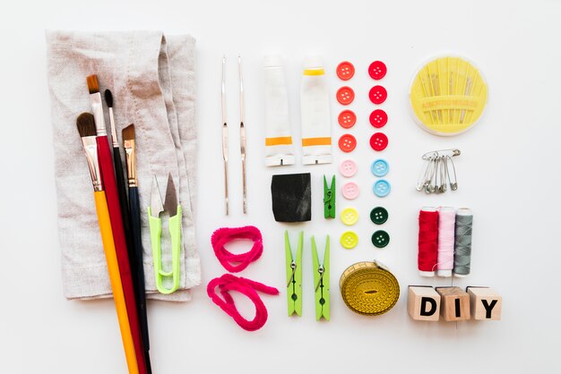 Diy apparatuur; penseel; wasknijper; naald; veiligheidsspelden; acryl verf buis; toetsen; diy blokken en meetlint geïsoleerd op een witte achtergrond