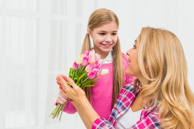 Gratis foto dochter die roze tulpenbloemen geeft aan moeder