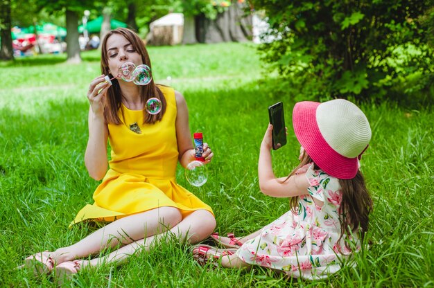 Dochter het nemen van een foto van haar moeder, terwijl het maken van bubbels