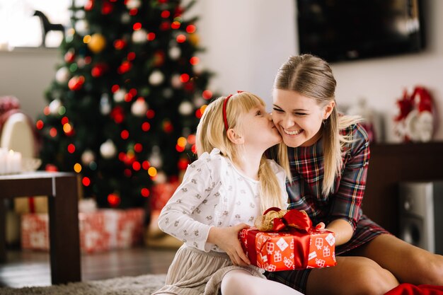 Dochter kussende moeder bij Kerstmis