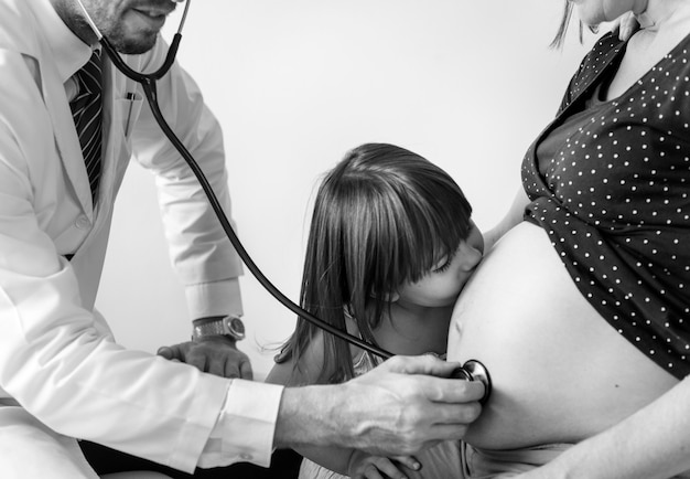Dochter kust zwangere moeders buik tijdens foetale monitoring