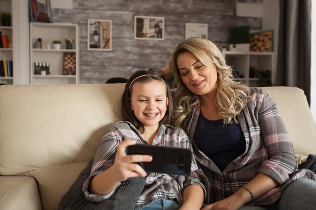 Dochter met beugels en haar moeder kijken naar een video op smartphone.