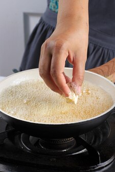 Doe gele aziatische traditionele tofu met poedercoating op hete olie in een pan, kookproces in de keuken chinees maken of eten