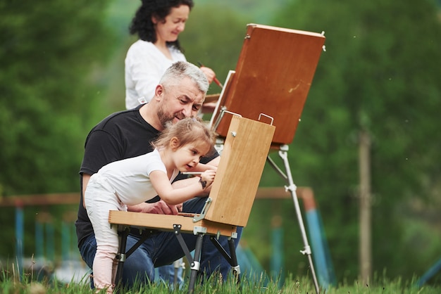 Doe ik dat goed? grootmoeder en grootvader hebben buiten plezier met kleindochter. schilderij conceptie