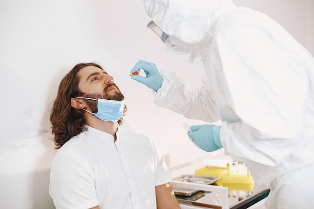 Gratis foto dokter beschermend pak en chirurgisch gezichtsmasker. wattenstaafje uit de keel en neus van de patiënt. coronavirus-test, test voor covid-19-infectie in een pandemie.