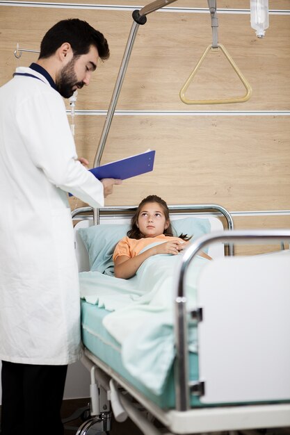 Dokter bezoek patiënt meisje in het ziekenhuis. Tienermeisje dat in het ziekenhuisbed ligt