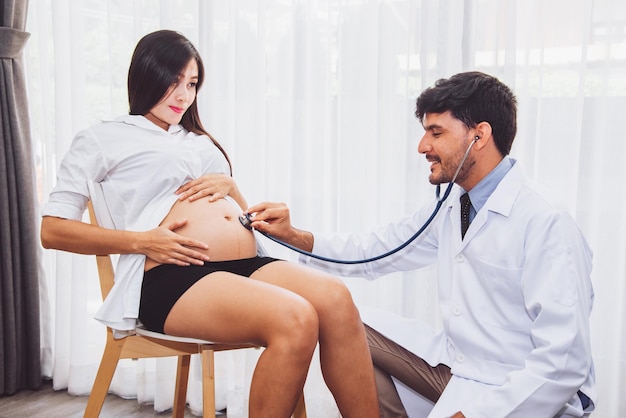 Dokter controleert zwangere vrouw met stethoscoop in het ziekenhuisgezondheidszorgconcept