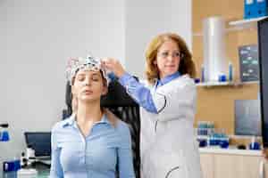Gratis foto dokter die hersengolven scanapparaat op het hoofd van de patiënt aanpast. hersen- en neurologiestadium