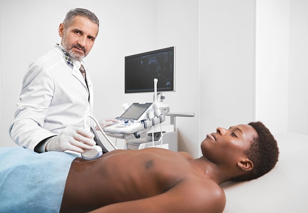 Dokter die naar de camera kijkt terwijl hij een ultrasone diagnose stelt