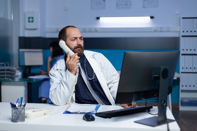 Dokter gebruikt vaste telefoon voor communicatie op afstand overuren