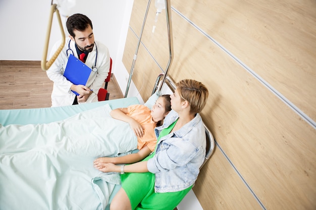 Dokter geeft het nieuws aan geduldig meisje en moeder in het ziekenhuis
