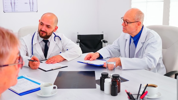 Dokter houdt presentatie over symptomen van patiënten voor medisch team dat onderzoeksstappen plant. Medisch team met conferentie over mensenziekte zittend in ziekenhuiskantoor