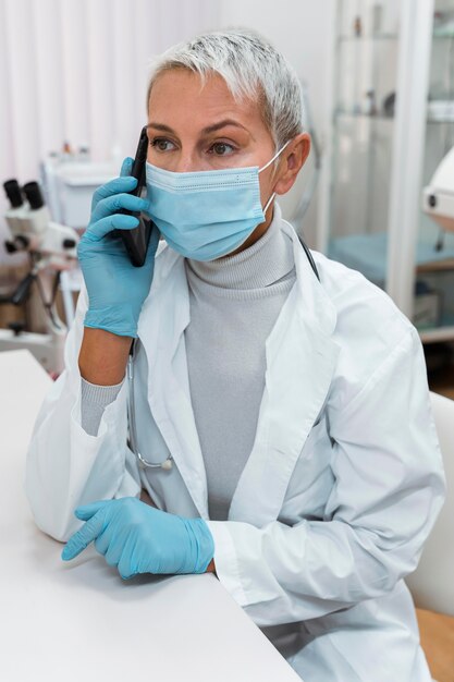 Dokter praat met haar telefoon terwijl ze een medisch masker draagt