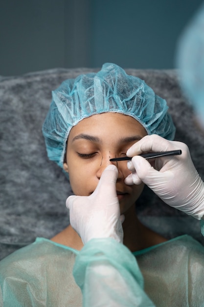 Gratis foto dokter tekenen met marker op gezicht hoge hoek