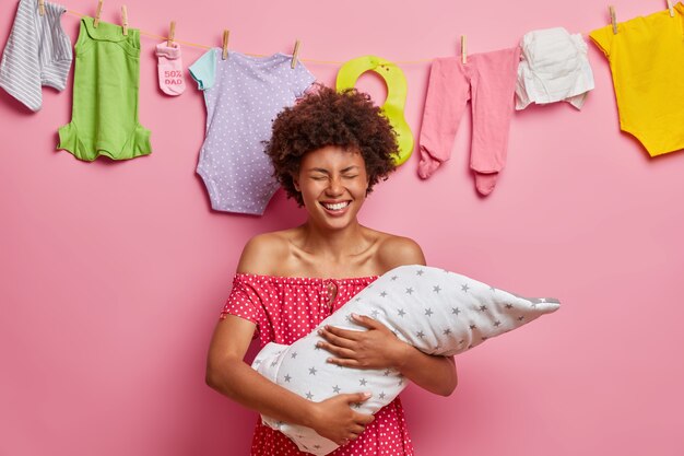 Dolblij moeder met pasgeboren baby op handen geniet van het zoete moment van het moederschap als moeder voor de eerste keer poseert