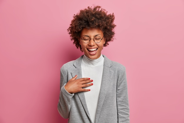 Dolblij professionele vrouwelijke manager kan niet stoppen met lachen, hoort grappige grap van collega, draagt zakelijke outfit, grinnikt positief