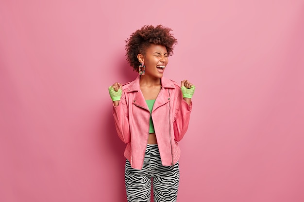 Dolblij, slanke vrouw heeft afro haar vuisten van vreugde, voelt zich erg gelukkig en gelukkig na een training in de sportschool