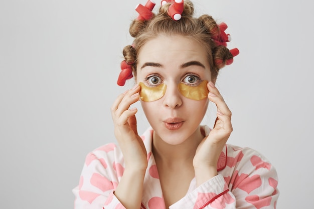 Dom schattig meisje in haarkrulspelden en nachtkleding ooglapjes toepassen