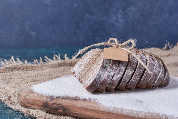 Donker brood gebonden met rustieke draad op blauwe tafel.