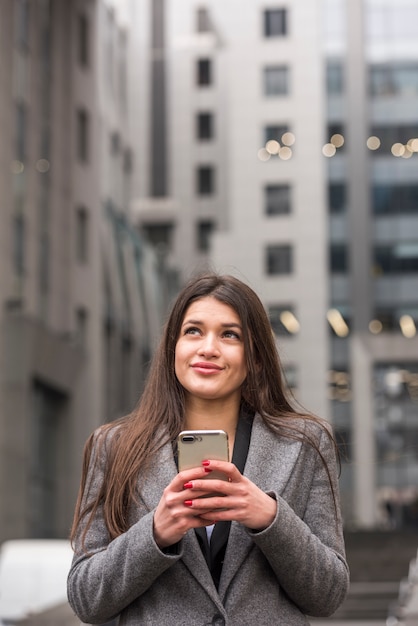 Donkerbruine onderneemster die haar smartphone gebruikt