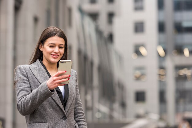 Donkerbruine onderneemster die haar smartphone gebruikt