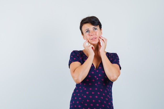 Donkerbruine vrouw die angstgebaar in paars en rood gedessineerde jurk uiten en op zoek bedroefd. vooraanzicht.