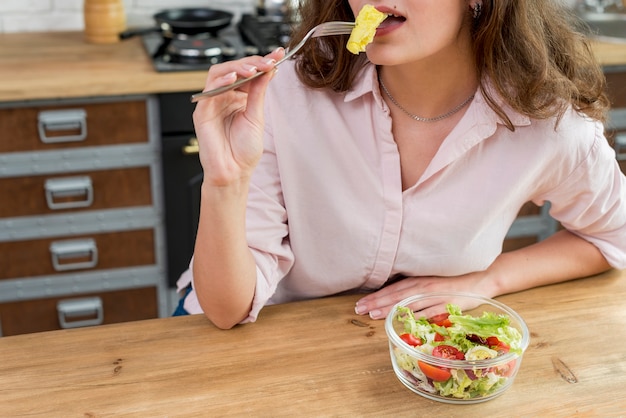 Donkerbruine vrouw die een salade eet