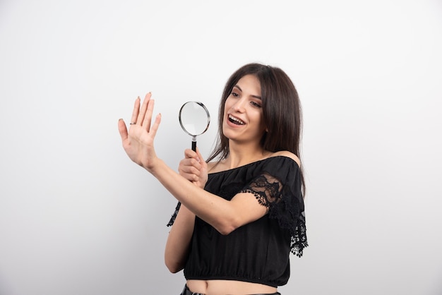 Donkerbruine vrouw die haar hand met vergrootglas bekijkt.