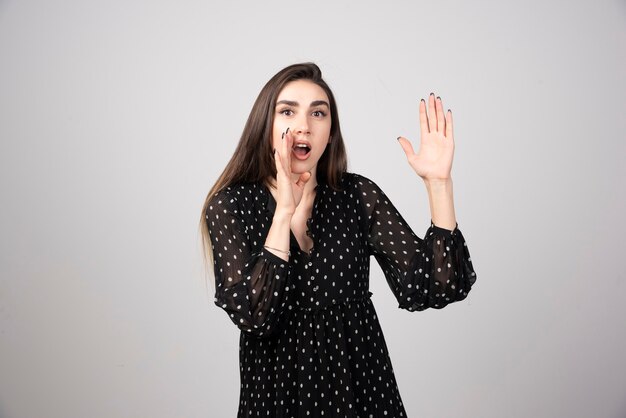 Donkerbruine vrouw die in zwarte kleding iemand roept.