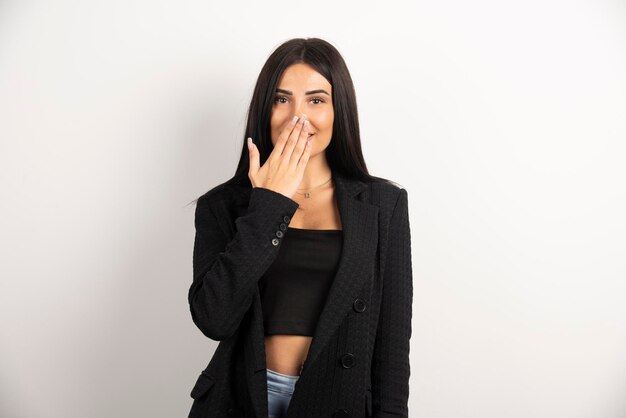 Donkerbruine vrouw in zwarte crop top die haar mond bedekt. Hoge kwaliteit foto