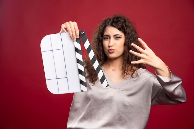 Gratis foto donkerbruine vrouw met filmklapper die haar hand toont.