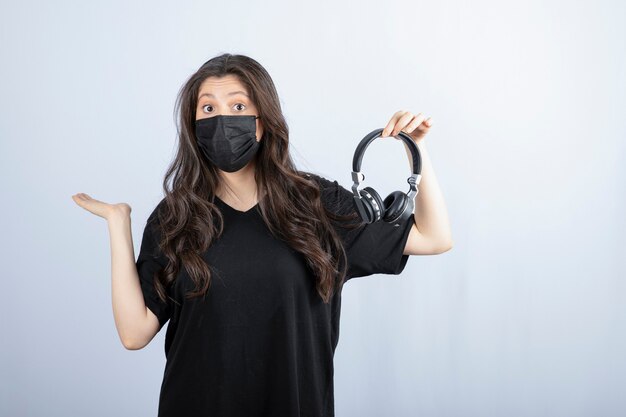 Donkerbruine vrouw met lang haar in de medische hoofdtelefoon van de maskerholding.