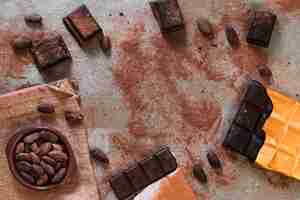 Gratis foto donkere chocoladereep met verspreid cacaopoeder en bonenkom