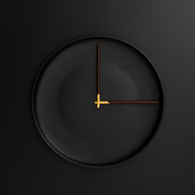 Donkere plaat met chocoladestokken in de vorm van een klok