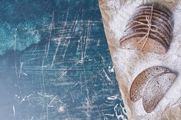 Donkere sneetje brood op blauwe tafel.