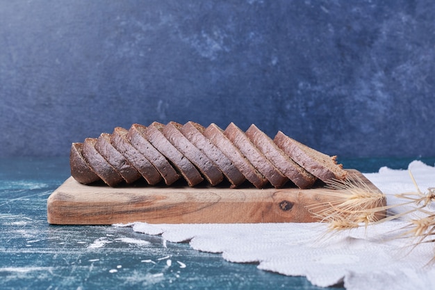 Donkere sneetjes brood op blauwe tafel.