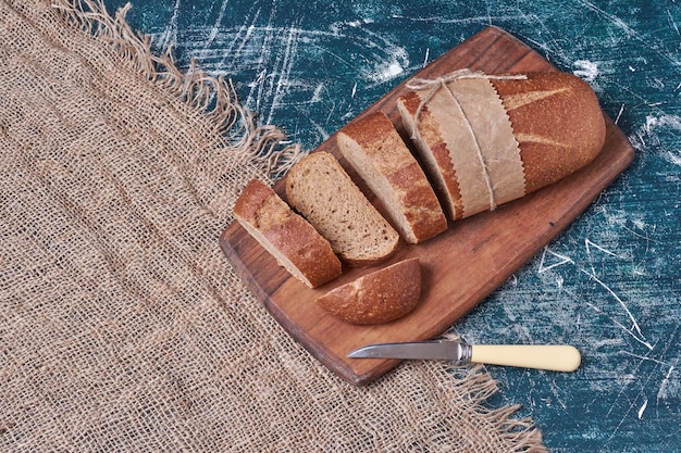 Donkere sneetjes brood op een houten bord.