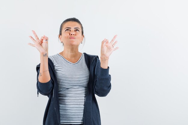 Donkerharige vrouw die ok gebaar toont terwijl het opzoeken in overhemd